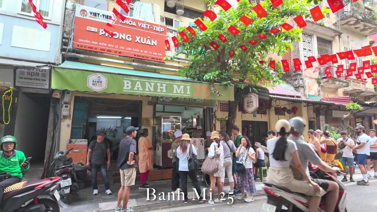 Áo thun trắng in hình các biểu tượng của Hà Nội như phố cổ, xe xích lô và chùa Một Cột.