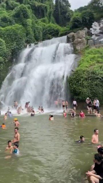 Du khách đang đi bộ trên con đường mòn khám phá cảnh quan xung quanh thác.