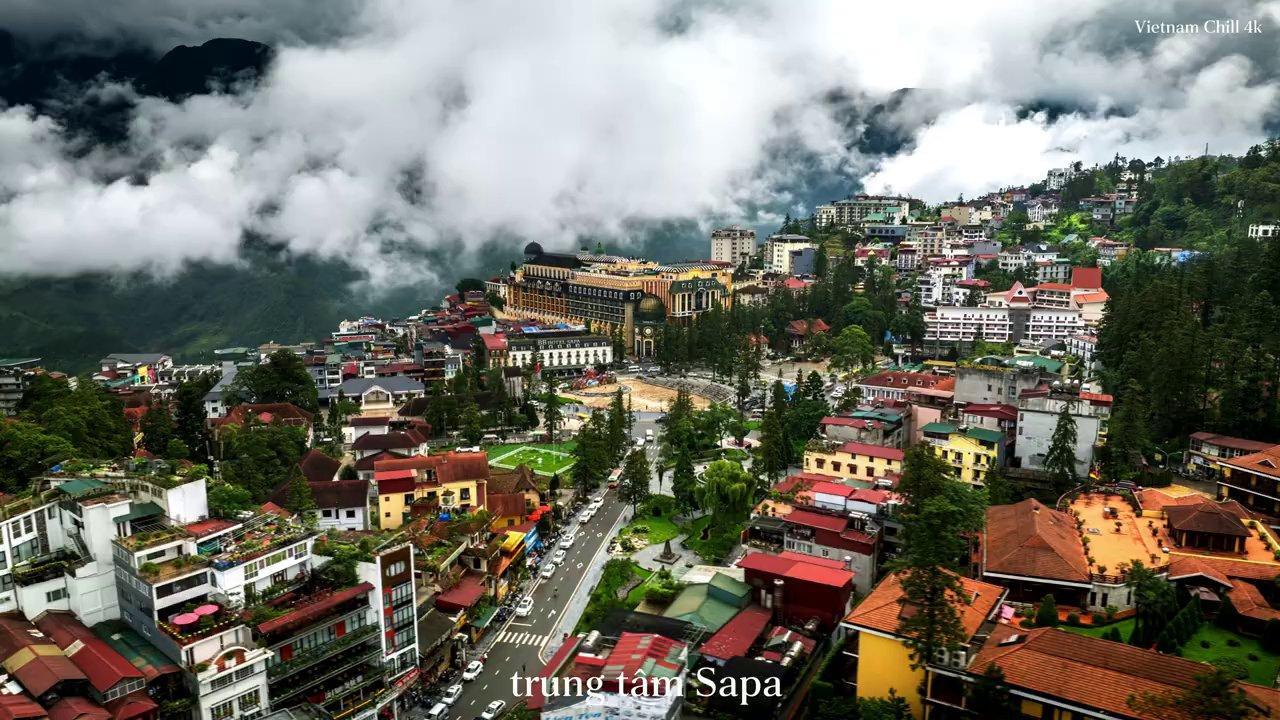 Đoàn tàu màu đỏ chạy trên đường sắt leo núi giữa khung cảnh núi non trùng điệp và những kiến trúc hiện đại của khu du lịch.