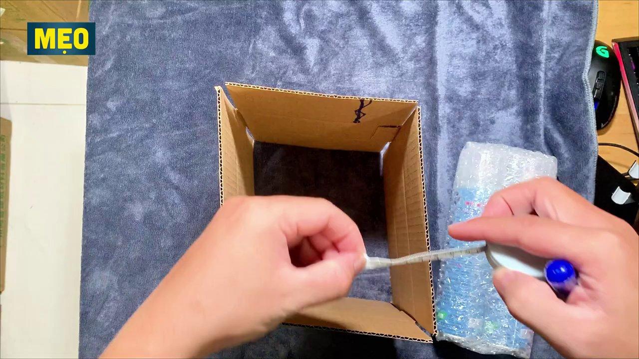 Phần carton thừa được gấp và đánh dấu để cắt bỏ, tạo kích thước mới vừa vặn với món đồ.