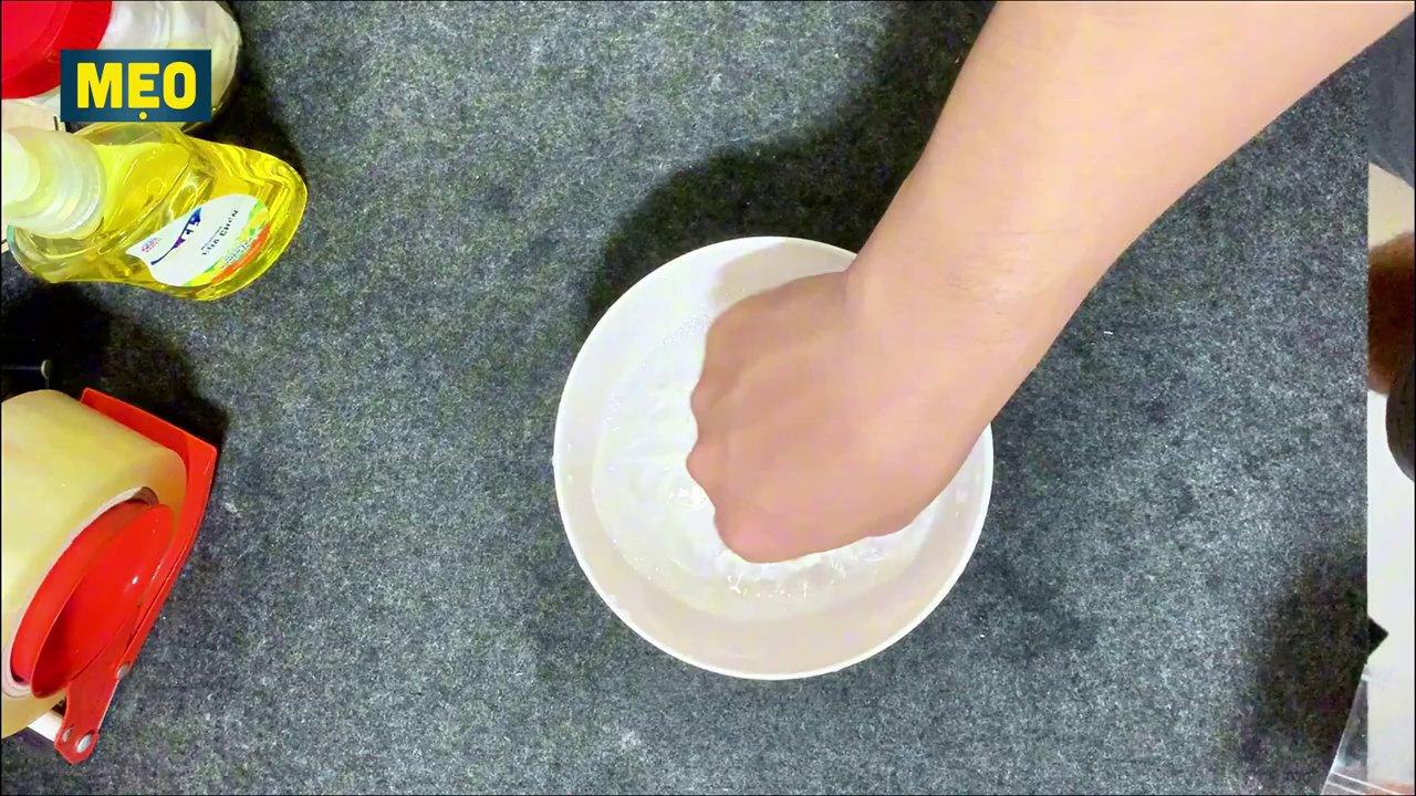 Miếng giấy in được dán băng keo, sau đó ngâm vào nước có pha nước rửa chén.
